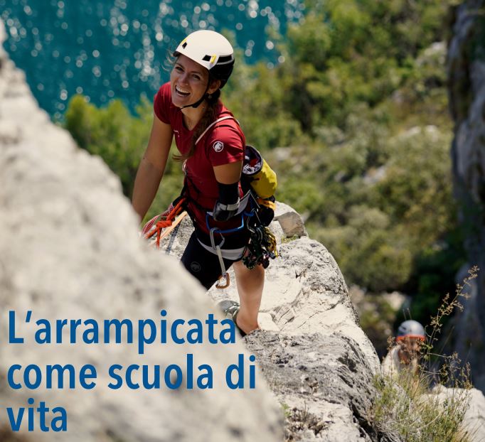 Ragazza priva dell'avambraccio sinistro arrampica su una scogliera. Sullo fondo, il mare