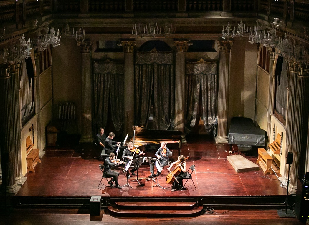 Cinque musicisti suonano sul palco, uno al pianoforte, quattro agli archi