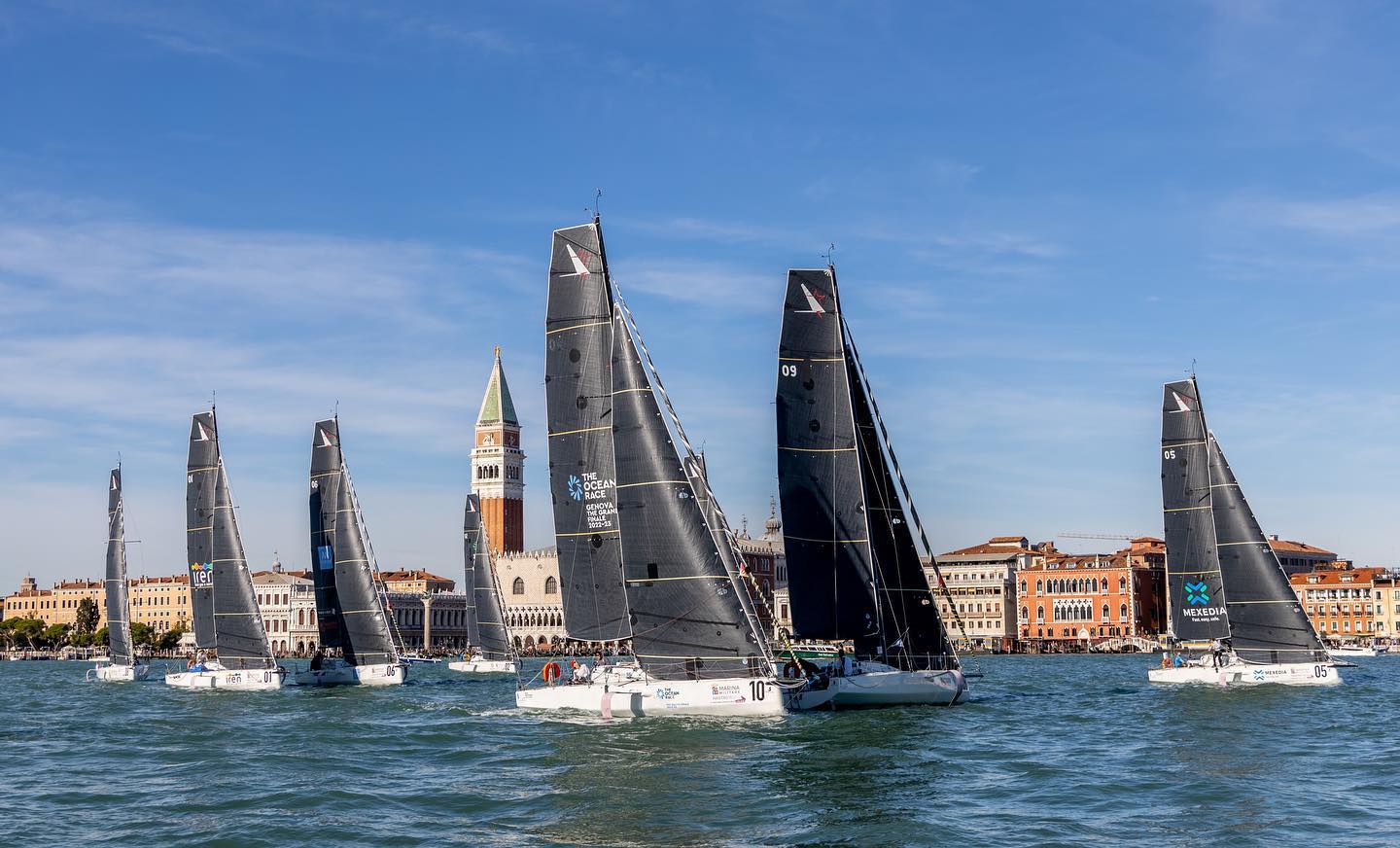 Sette barche a vela navigano nel bacino di San Marco; sullo sfondo il campanile di San Marco e Palazzo Ducale