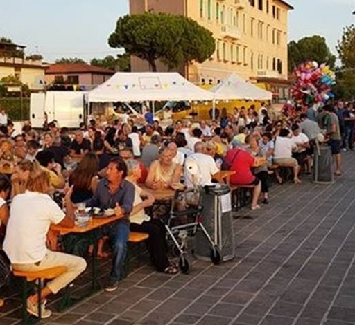 Moltitudine di persone sedute a tavoli da sagra