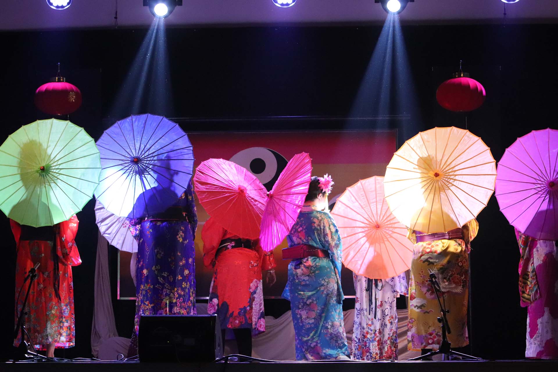 Sette persone vestite da geisha e che reggono un ombrellino viste di spalle