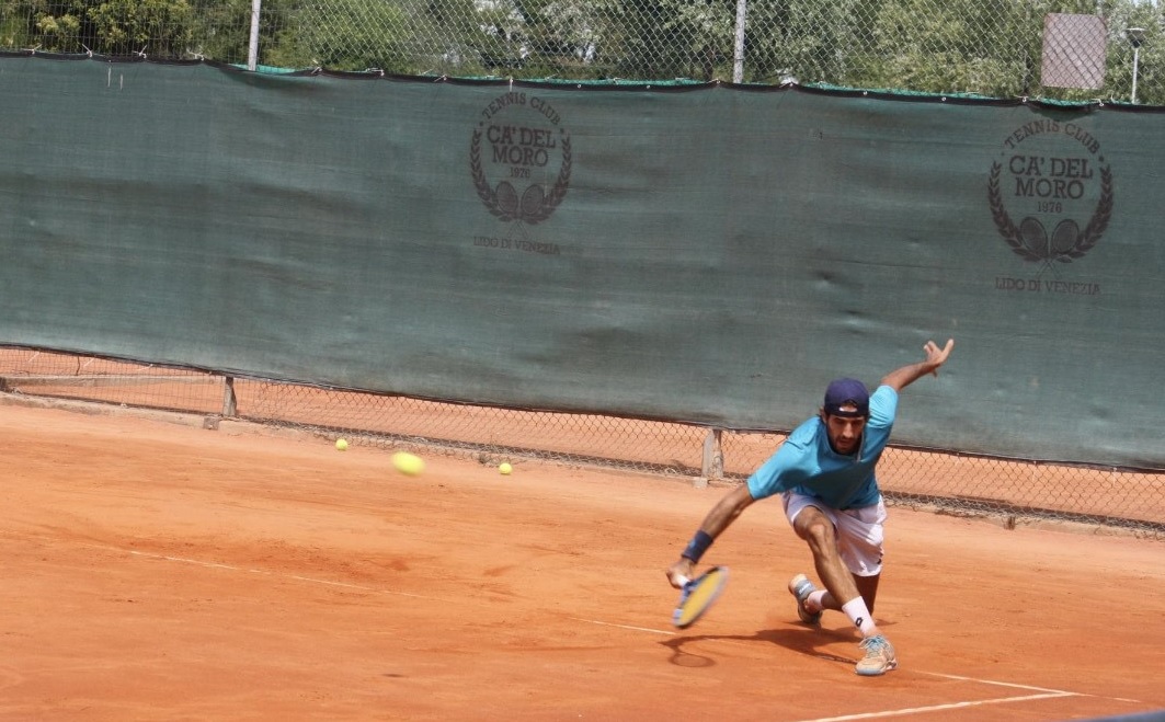 Tennista colpisce la pallina in allungo su un campo di terra battuta