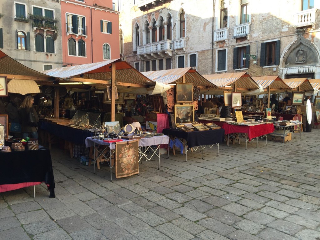 Fila di sei banchi di un mercatino allestito in un campo di Venezia