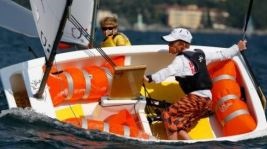 Ragazzo con occhiali da sole e berretto col frontino a bordo di una barca a vela durante una regata