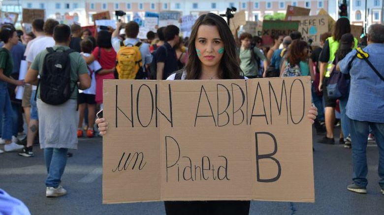 Un ragazza regge un cartello con la scritta "Non abbiamo un Pianeta B". Sullo sfondo, una folla.