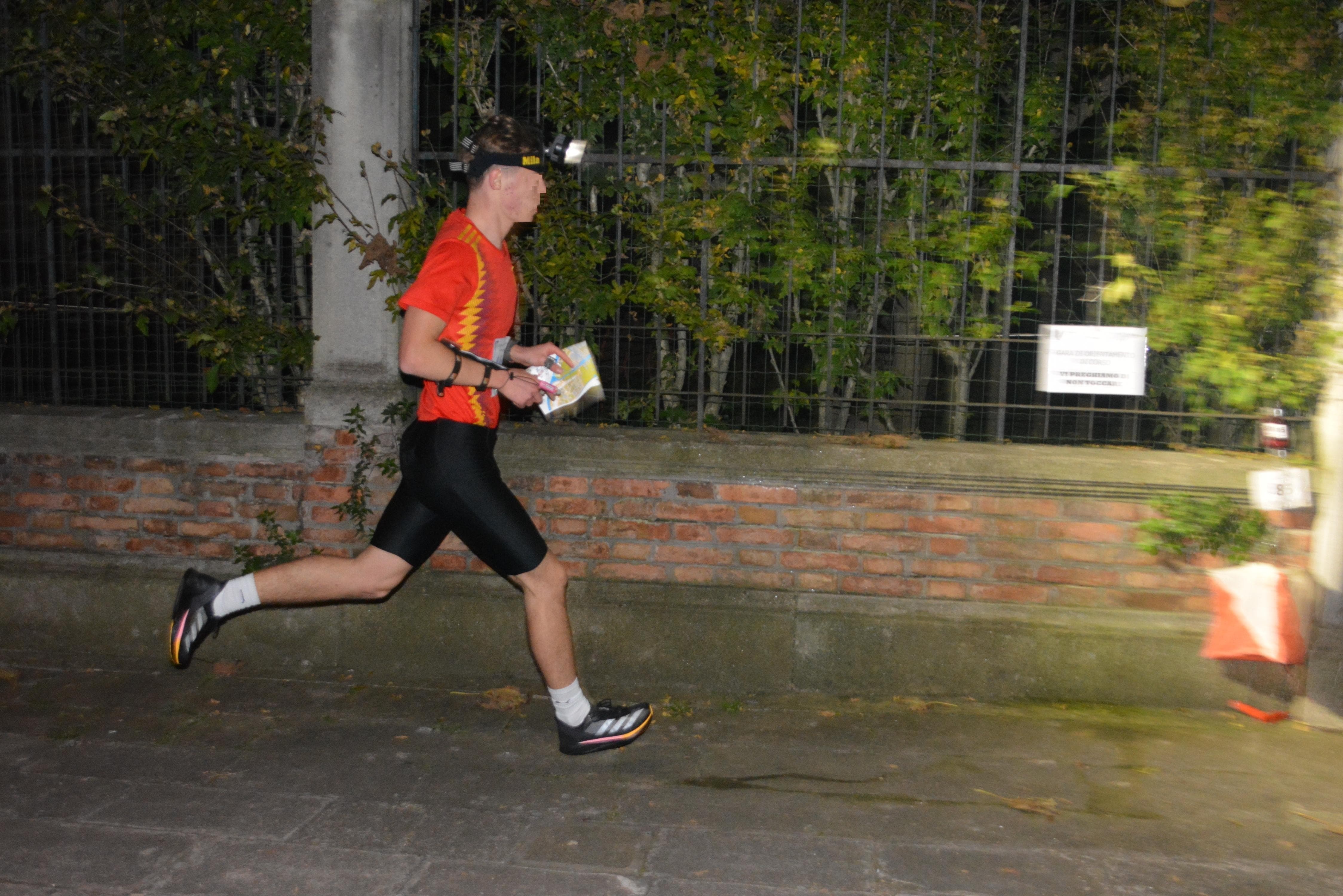 Ragazzo di profilo corre con una torcia sulla fronte e una mappa in mano