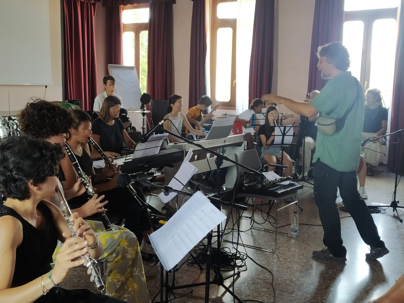 Una classe di bambini e adolescenti suona clarinetti, flauti e chitarre guidata dal maestro