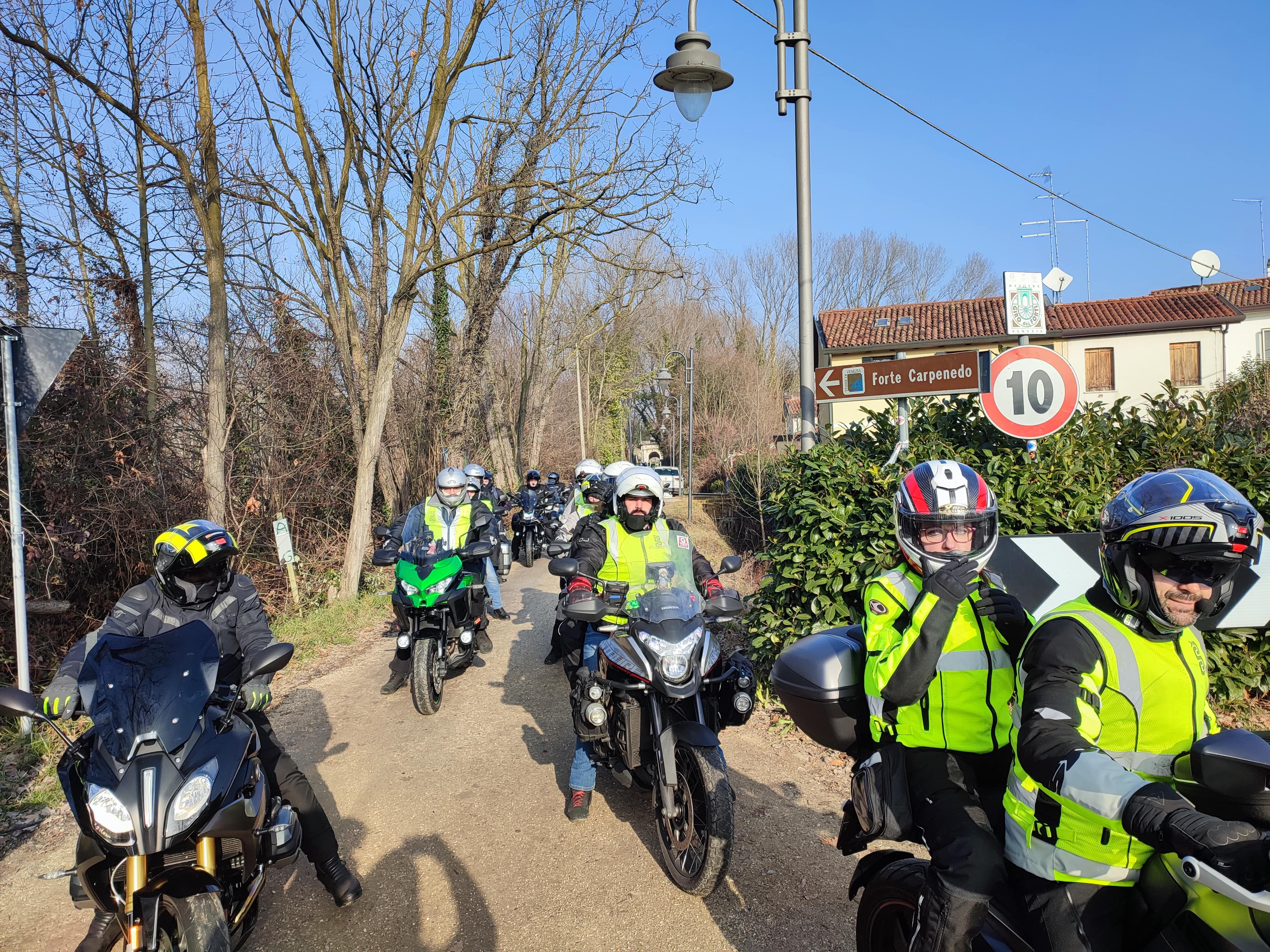 Gruppo di motociclisti in colonna su una strada alberata