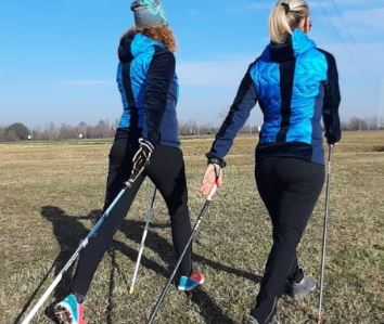 Due donne, viste di spalle, praticano nordic walking