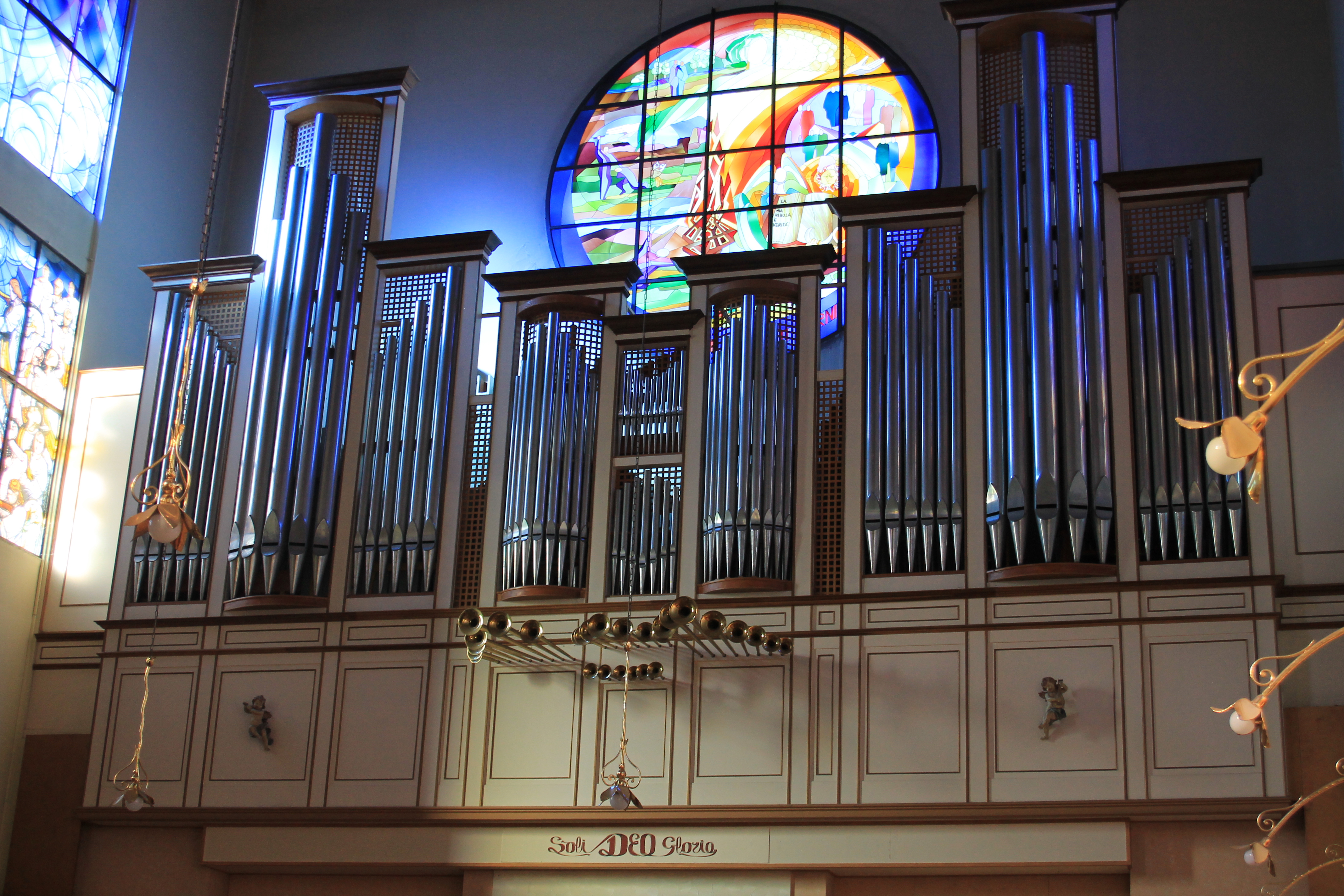 Grande organo di una chiesa. Sopra, un rosone istoriato.