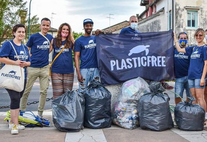 Sette attivisti ambientalisti reggono uno striscione con scritto "Plasticfree" davanti ai sacchi coi rifiuti appena  raccolti