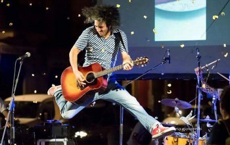 Chitarrista con folti ricci salta suonando sul palco