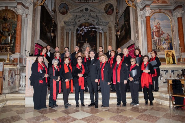 Coro misto, maschile e femminile, di una ventina di persone in posa su due file all'interno di una chiesa