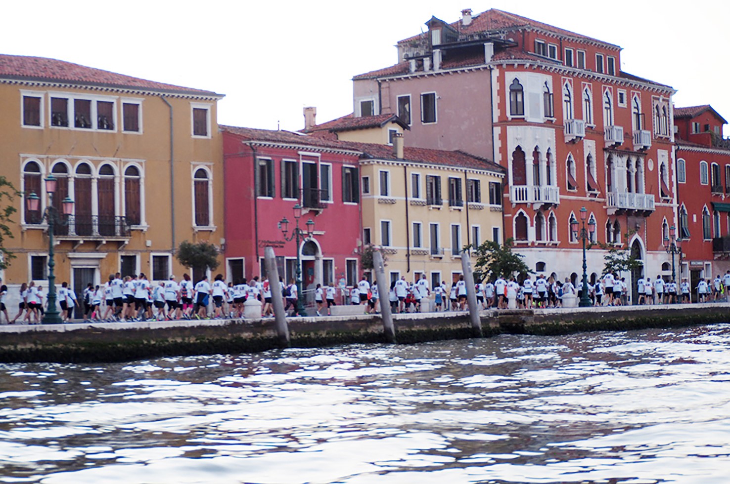 Una fila di persone con la stessa maglietta cammina su una riva di Venezia