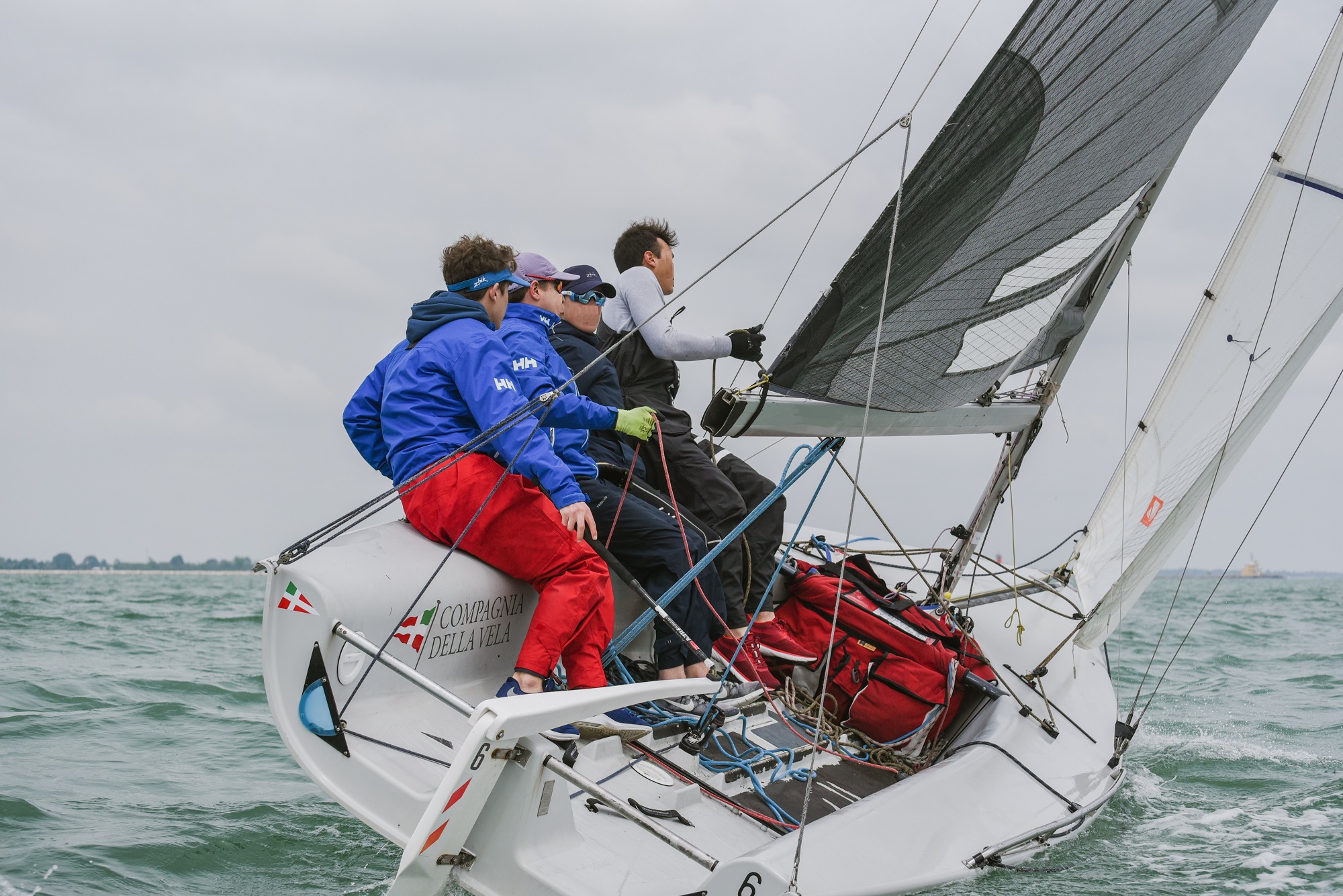 Tre ragazzi a bordo di una barca a vela sportiva